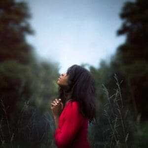 A woman in red shirt standing on grass field.